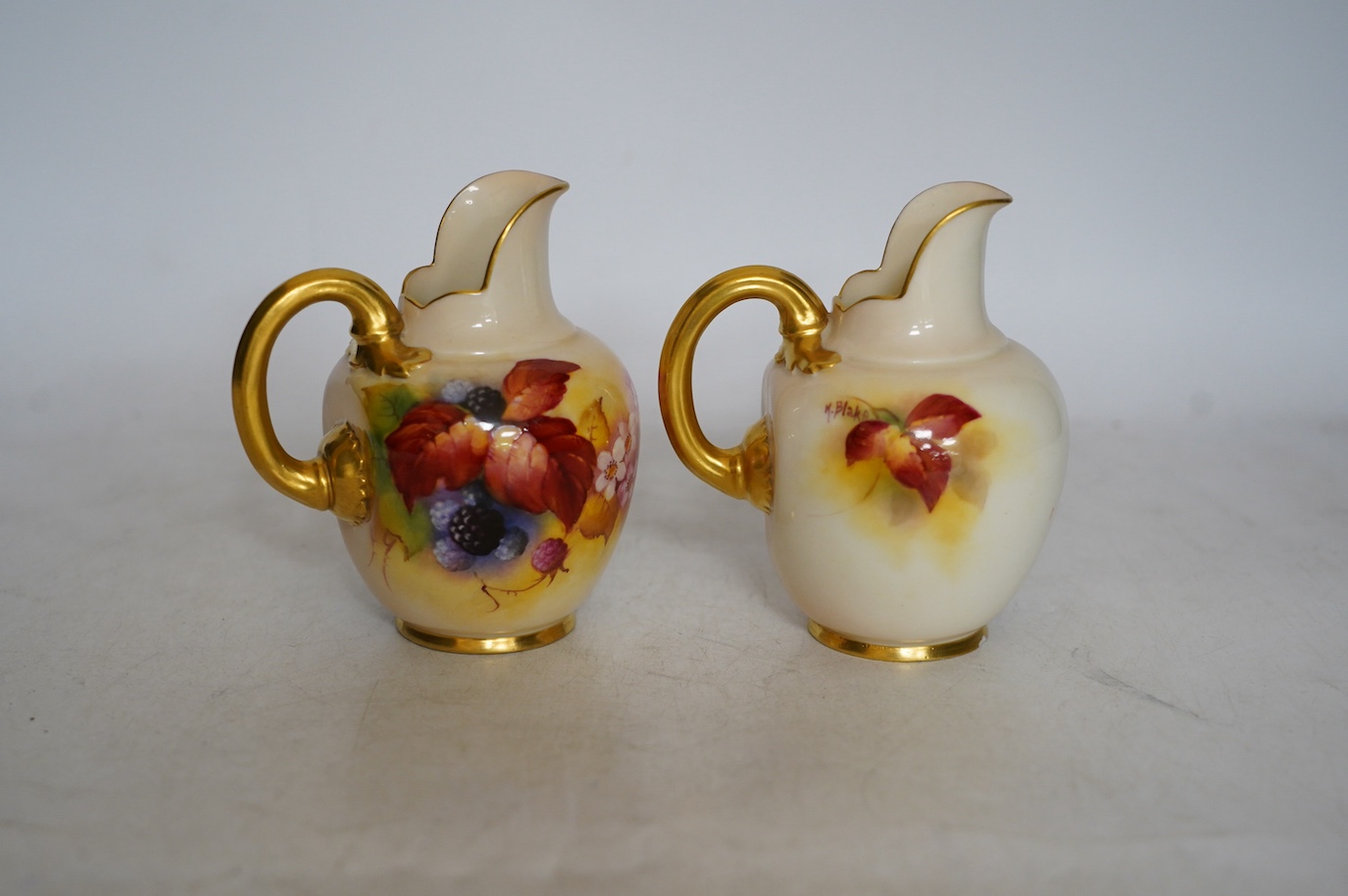 Kitty Blake for Royal Worcester, a pair of porcelain ewers, hand painted with autumn leaves and berries, shape 1094, 11cm. Condition - good